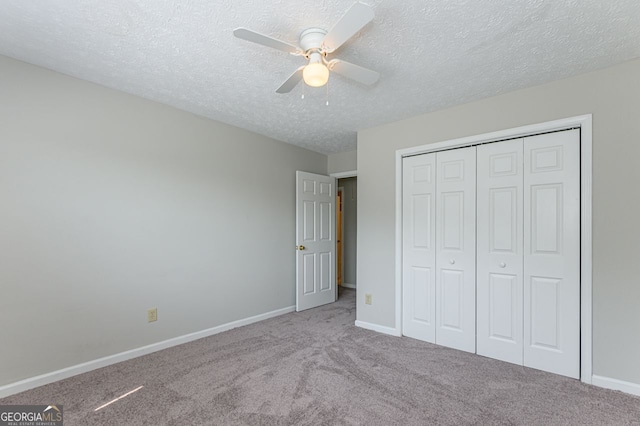 unfurnished bedroom with light carpet, a textured ceiling, ceiling fan, and a closet