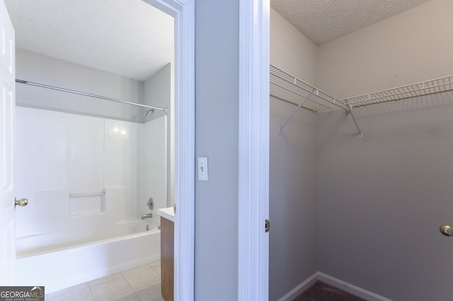 bathroom featuring tile patterned flooring, shower / washtub combination, and a textured ceiling