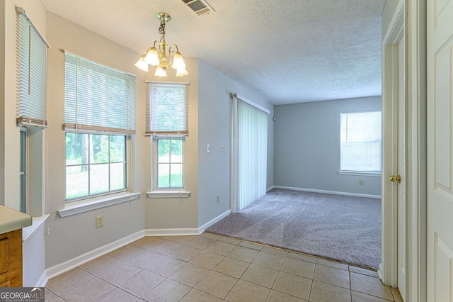 interior space featuring an inviting chandelier, light tile patterned floors, and a textured ceiling