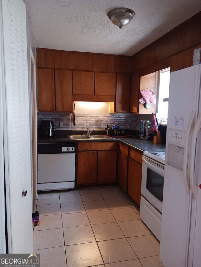 kitchen featuring tasteful backsplash, white appliances, sink, a textured ceiling, and light tile patterned floors