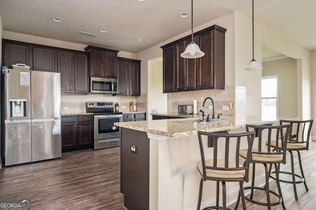 kitchen with appliances with stainless steel finishes, tasteful backsplash, dark wood-type flooring, and pendant lighting