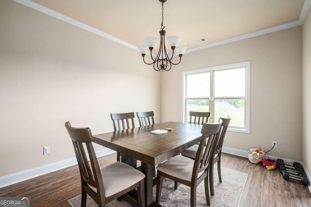 dining space featuring crown molding, hardwood / wood-style flooring, and an inviting chandelier