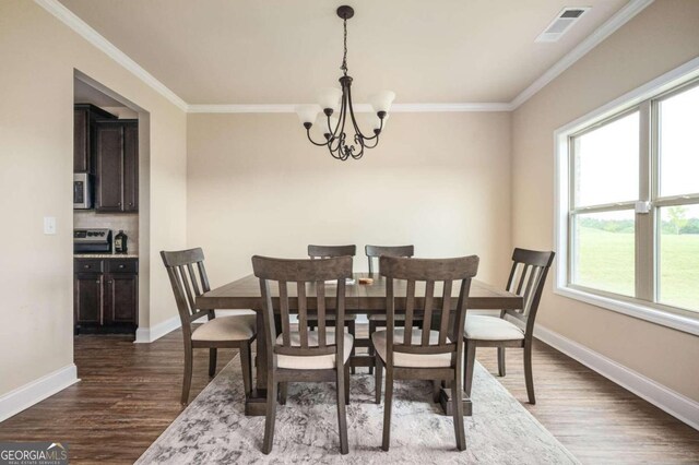 dining area with ornamental molding, dark hardwood / wood-style flooring, and an inviting chandelier