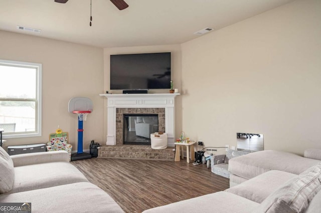 living room with hardwood / wood-style floors, ceiling fan, and a brick fireplace