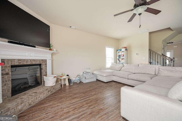 living room featuring wood-type flooring, a fireplace, and ceiling fan