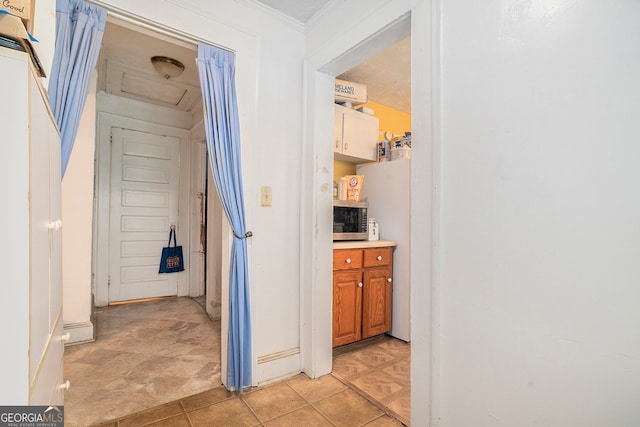 hall featuring light tile patterned flooring and ornamental molding