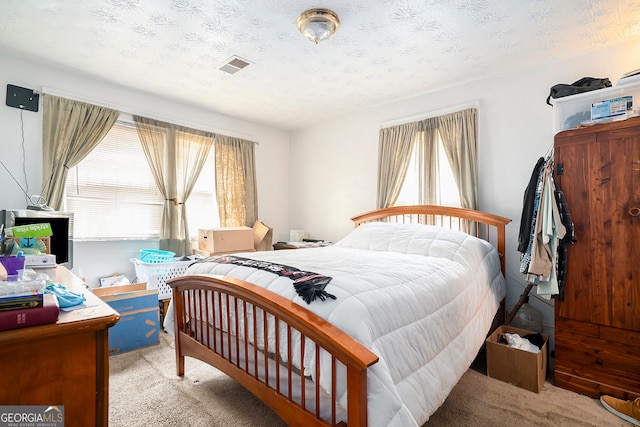 bedroom with a textured ceiling and light carpet