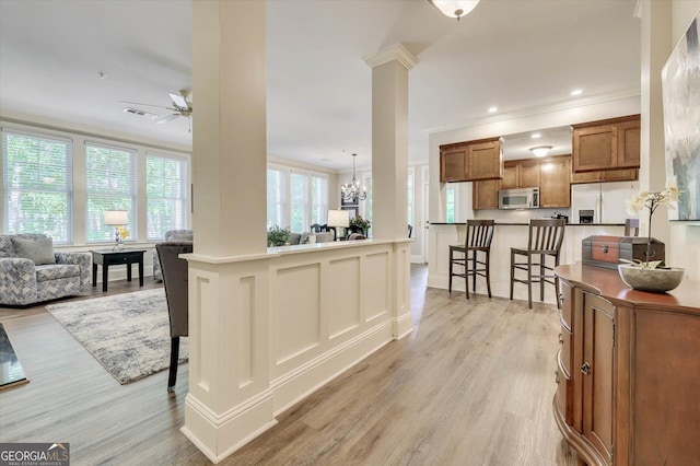 kitchen featuring ornamental molding, a kitchen bar, ornate columns, and appliances with stainless steel finishes