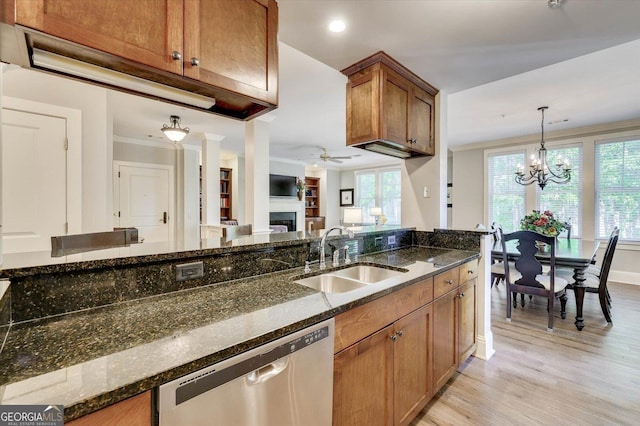 kitchen with dark stone counters, sink, hanging light fixtures, stainless steel dishwasher, and crown molding