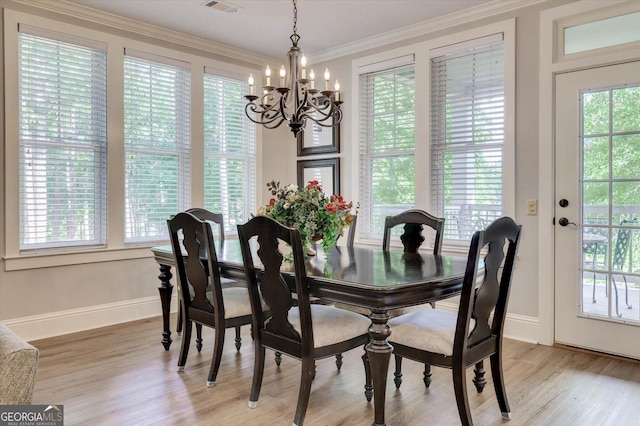 dining space with crown molding, light hardwood / wood-style floors, and a notable chandelier