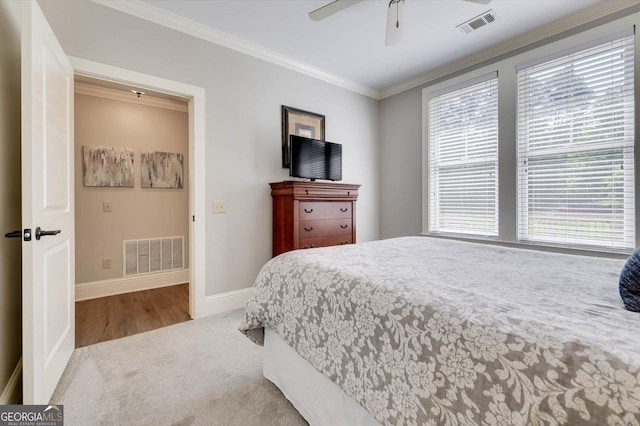 carpeted bedroom with ceiling fan and ornamental molding