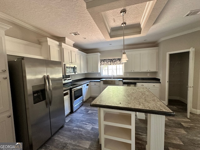 kitchen featuring a kitchen island, hanging light fixtures, white cabinetry, stainless steel appliances, and crown molding