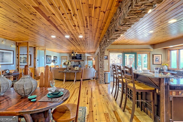 kitchen with dark stone counters, a center island, light hardwood / wood-style flooring, and wooden ceiling