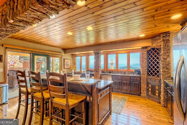 kitchen featuring light hardwood / wood-style flooring, dark stone countertops, wooden ceiling, appliances with stainless steel finishes, and a kitchen island