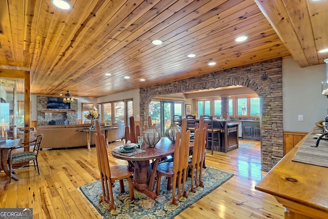 dining area featuring a fireplace, light hardwood / wood-style flooring, and wooden ceiling