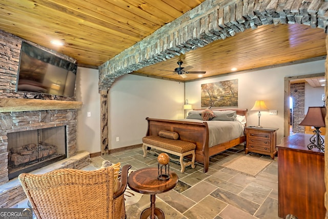 bedroom with a stone fireplace and wooden ceiling