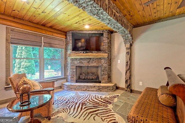 tiled living room with a stone fireplace and wooden ceiling