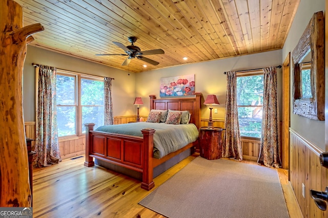 bedroom with ceiling fan, light hardwood / wood-style flooring, wood ceiling, and wood walls