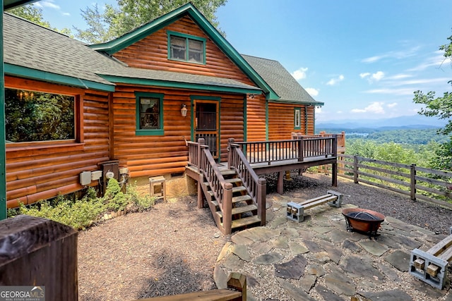 rear view of property featuring a fire pit, a wooden deck, and a patio area