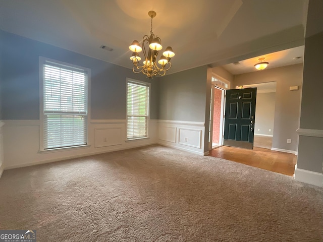 spare room with carpet and an inviting chandelier