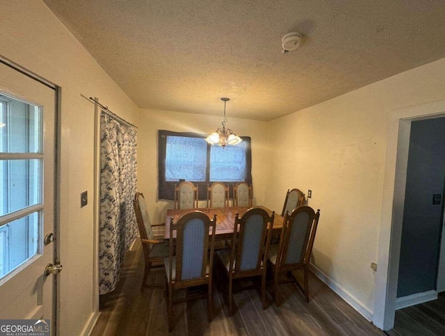 dining room with a textured ceiling, dark hardwood / wood-style flooring, and an inviting chandelier