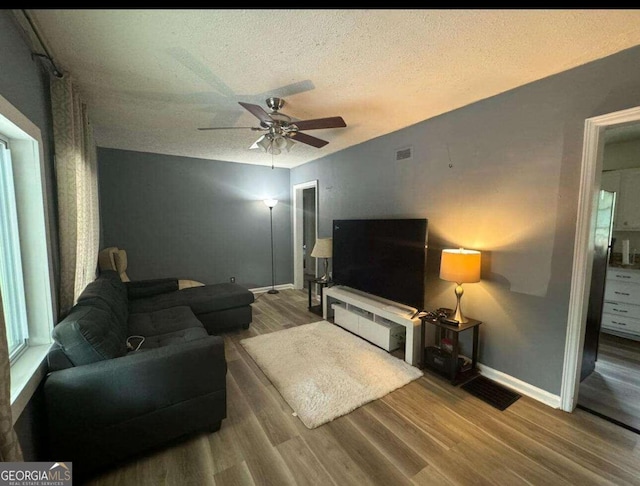 living room featuring a textured ceiling, ceiling fan, and hardwood / wood-style floors