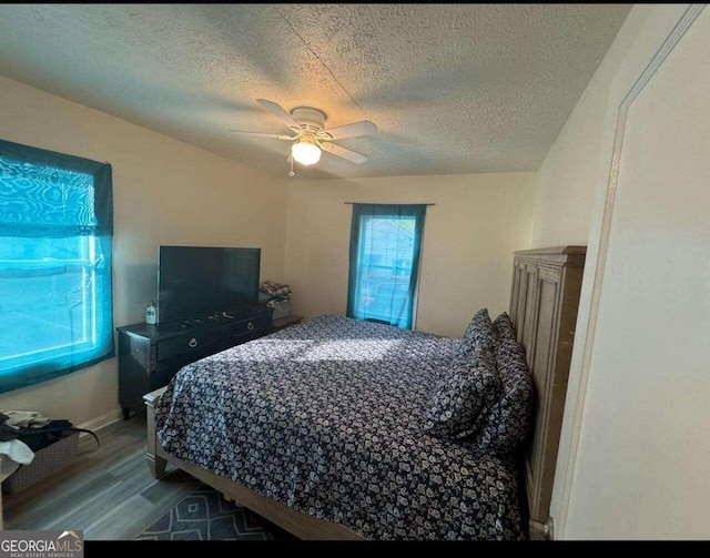 bedroom with a textured ceiling, ceiling fan, and hardwood / wood-style floors