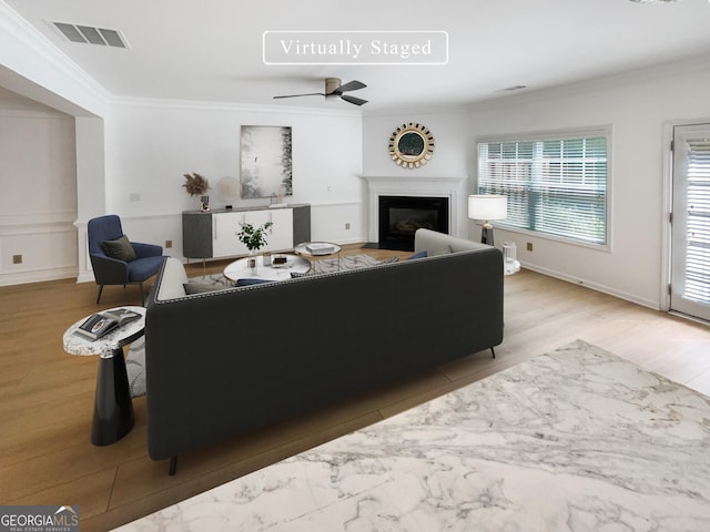 living room with hardwood / wood-style floors, ceiling fan, and ornamental molding