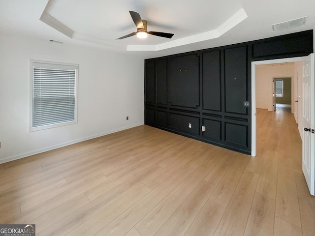 spare room featuring ceiling fan, a tray ceiling, and light wood-type flooring