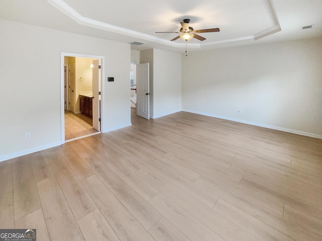 spare room featuring light hardwood / wood-style flooring, ceiling fan, and a raised ceiling