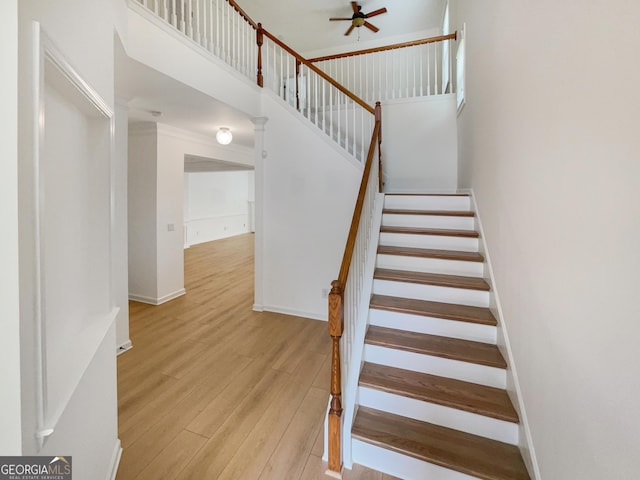 staircase featuring wood-type flooring and a high ceiling