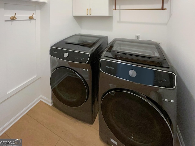 laundry area with light tile patterned floors, cabinets, and independent washer and dryer