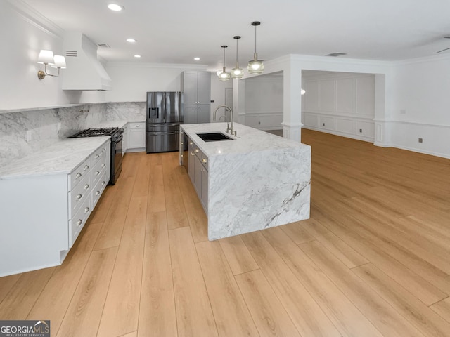 kitchen with light stone counters, black appliances, hanging light fixtures, and custom range hood