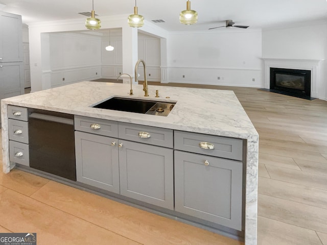 kitchen featuring sink, gray cabinets, decorative light fixtures, and light stone countertops