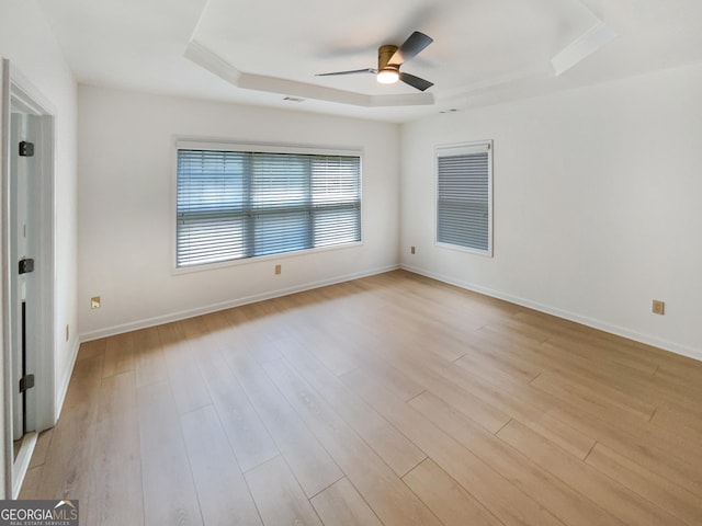 spare room featuring ceiling fan, light hardwood / wood-style floors, and a raised ceiling