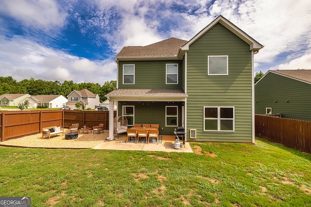 back of property with a lawn, a patio area, and an outdoor fire pit