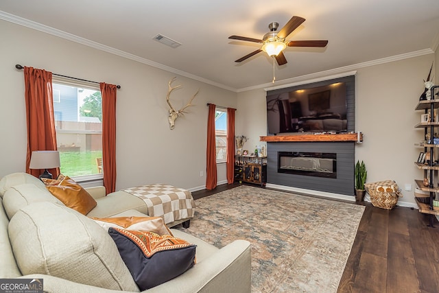 living room featuring a large fireplace, ornamental molding, dark hardwood / wood-style floors, and ceiling fan