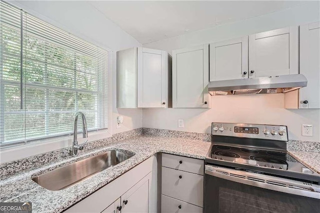 kitchen featuring white cabinetry, stainless steel electric range oven, light stone countertops, and sink