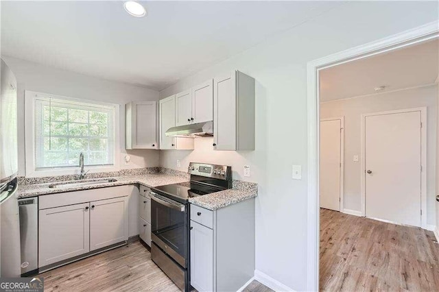 kitchen featuring light stone counters, appliances with stainless steel finishes, sink, and light wood-type flooring