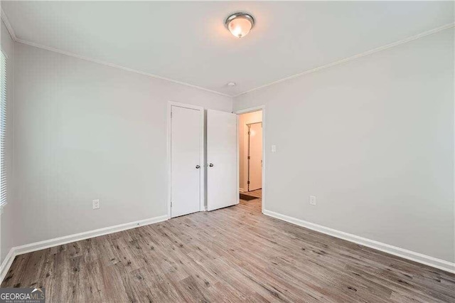 spare room with ornamental molding and light wood-type flooring