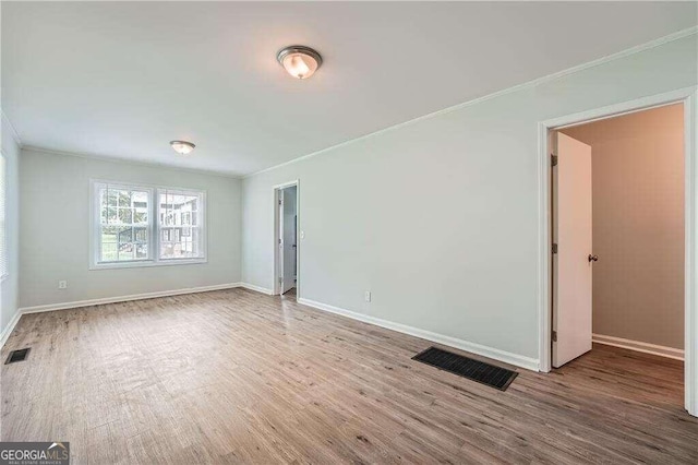 unfurnished room featuring hardwood / wood-style floors and ornamental molding