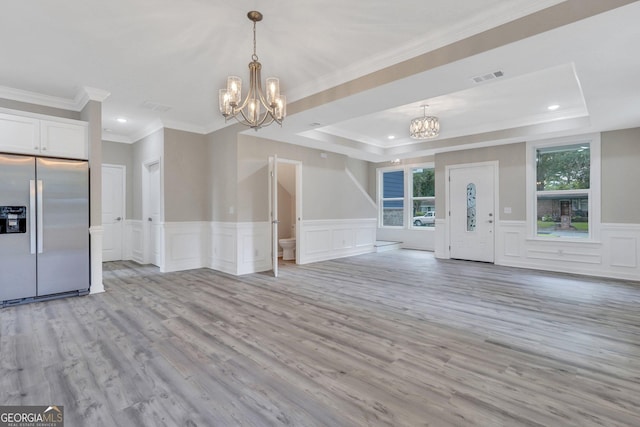 interior space featuring ornamental molding, light hardwood / wood-style flooring, an inviting chandelier, and a tray ceiling