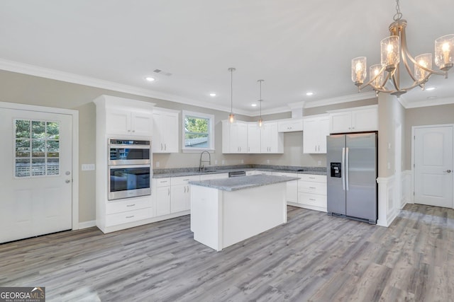 kitchen featuring appliances with stainless steel finishes, sink, decorative light fixtures, a kitchen island, and white cabinets