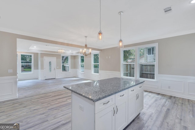 kitchen with pendant lighting, a raised ceiling, white cabinetry, dark stone countertops, and a chandelier