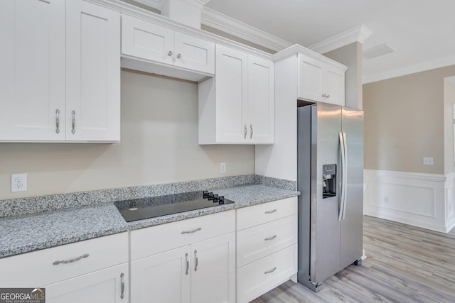 kitchen with light stone countertops, white cabinetry, stainless steel fridge with ice dispenser, black electric cooktop, and crown molding