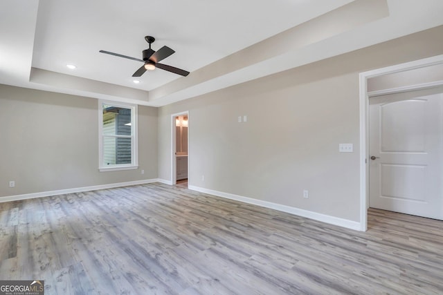 empty room featuring light hardwood / wood-style floors, a raised ceiling, and ceiling fan