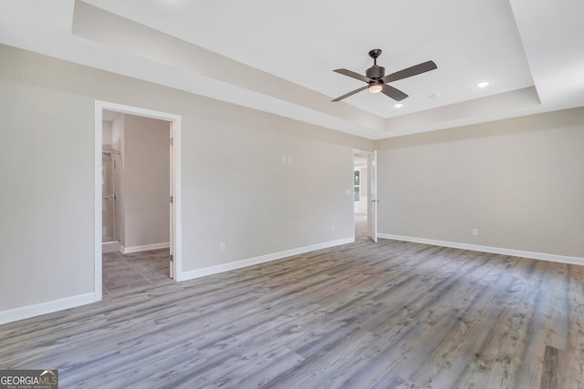 spare room featuring light hardwood / wood-style flooring, ceiling fan, and a raised ceiling