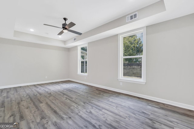 empty room featuring hardwood / wood-style floors, ceiling fan, and a raised ceiling