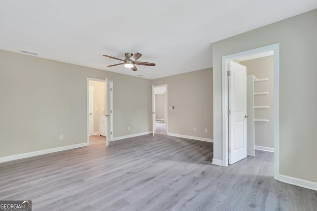 interior space featuring ceiling fan, a spacious closet, and light wood-type flooring