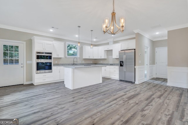 kitchen featuring white cabinetry, a center island, hanging light fixtures, and appliances with stainless steel finishes